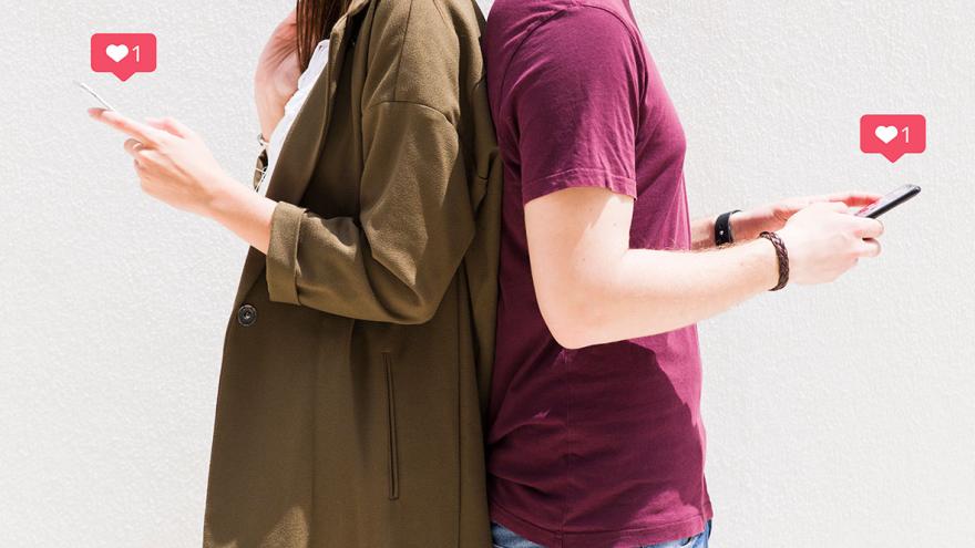 Ein Paar steht Rücken an Rücken, beide halten Smartphones und kommunizieren über eine Dating-App